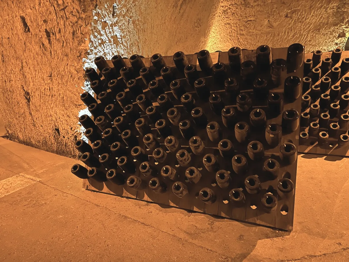 Botellas inclinadas en pupitres de removido dentro de las cavas subterráneas de Veuve Clicquot, Reims