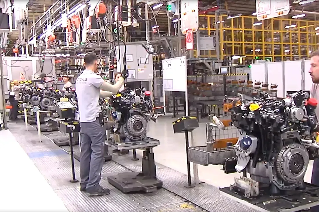Línea de montaje en la factoría Renault de Valladolid, con operarios trabajando sobre bloques motor en línea industrial