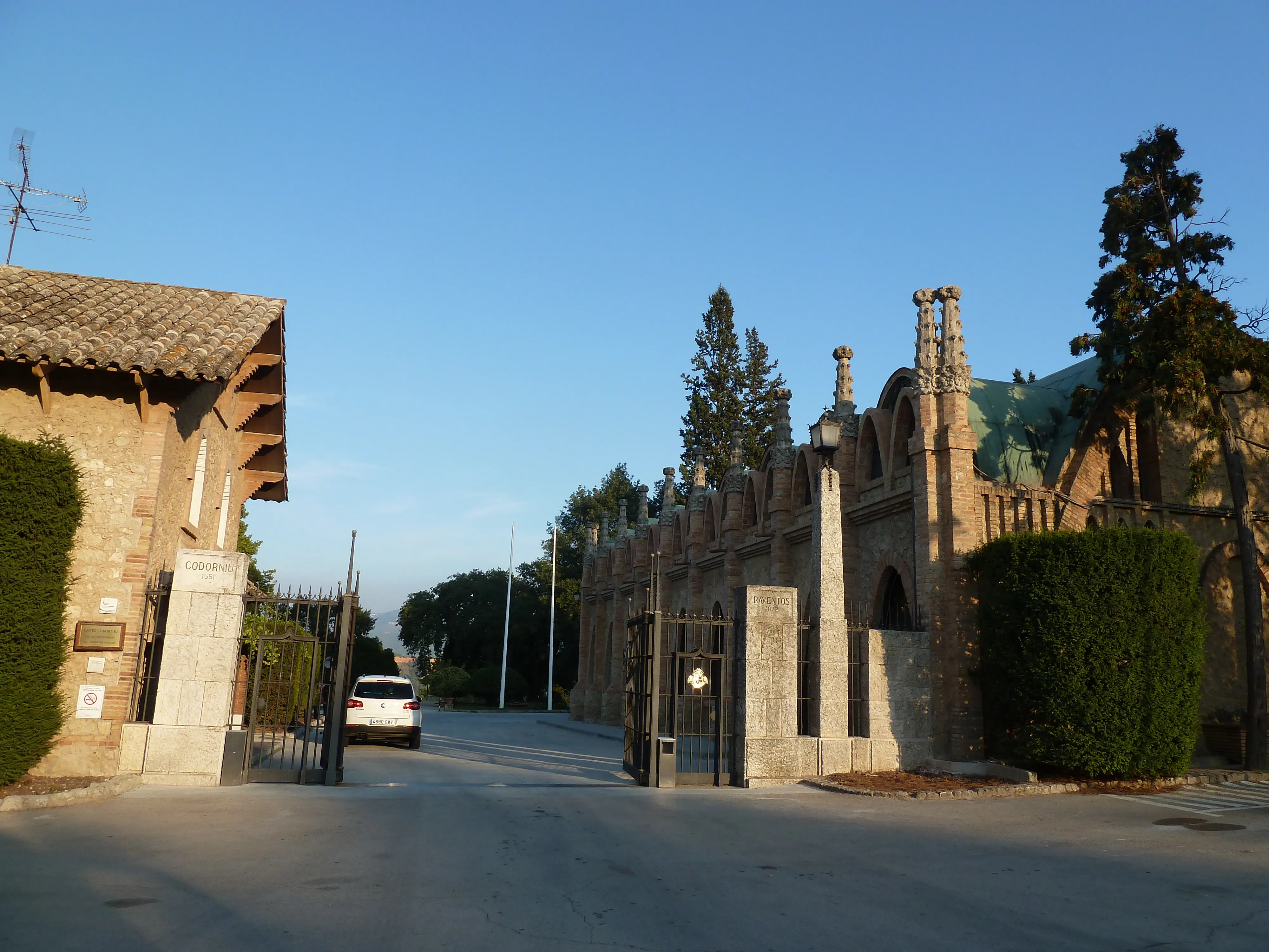 Entrada y verja del recinto de Caves Codorníu en Sant Sadurní d'Anoia, con caseta de control y conjunto modernista al fondo